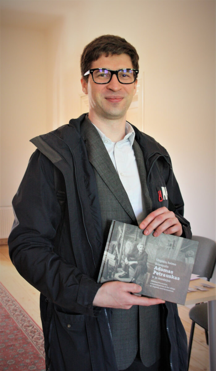 Rasmus Kask iš Estijos džiaugiasi padovanotu leidiniu „Uoginių kaimo šviesuolis Adomas Petrauskas ir jo muziejus“.